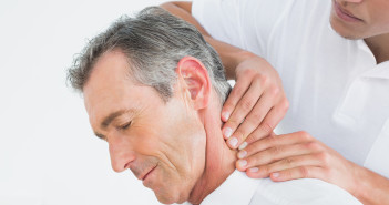 Close-up of a male chiropractor massaging patients neck over whi