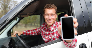 Smartphone man in car driving showing smart phone display smilin